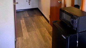 A hotel bathroom with a wooden door, a sink, a mirror, and a microwave. - Motel 6 Marianna, FL (Marianna)