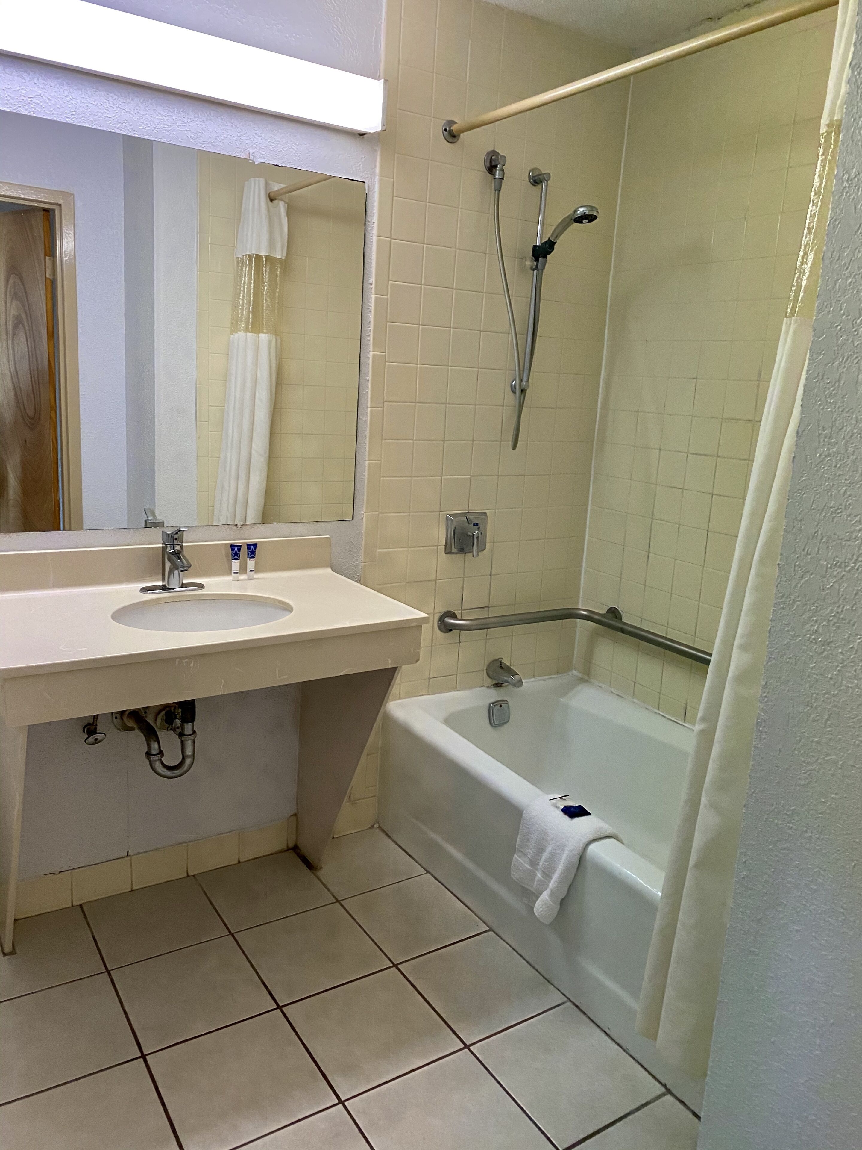 Un baño con lavamanos, espejo, bañera y ducha.