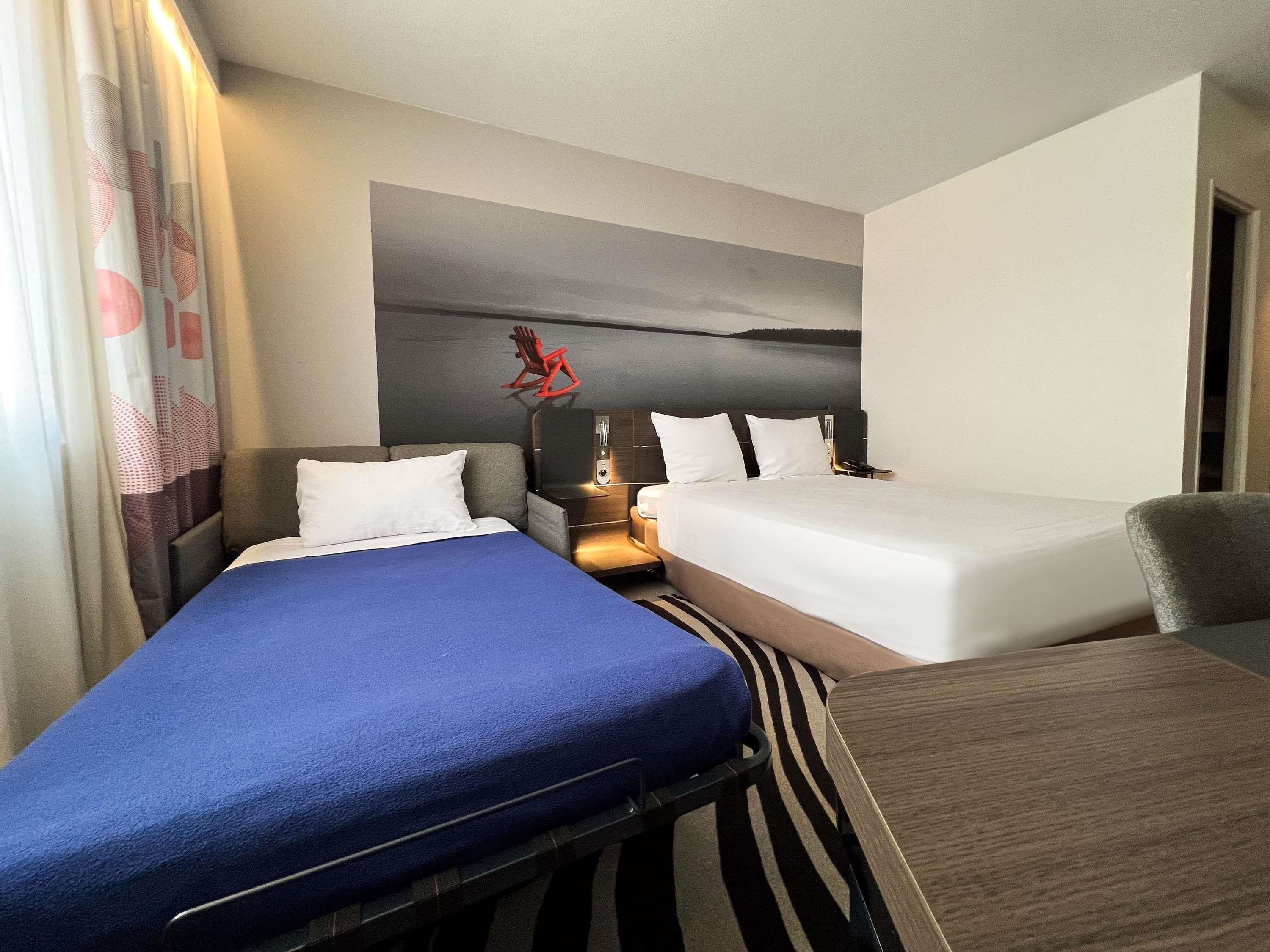 A hotel room with two beds, a desk, and a nightstand.
