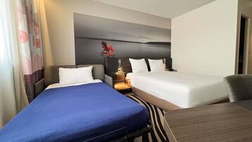 A hotel room with two beds, a desk, and a nightstand.