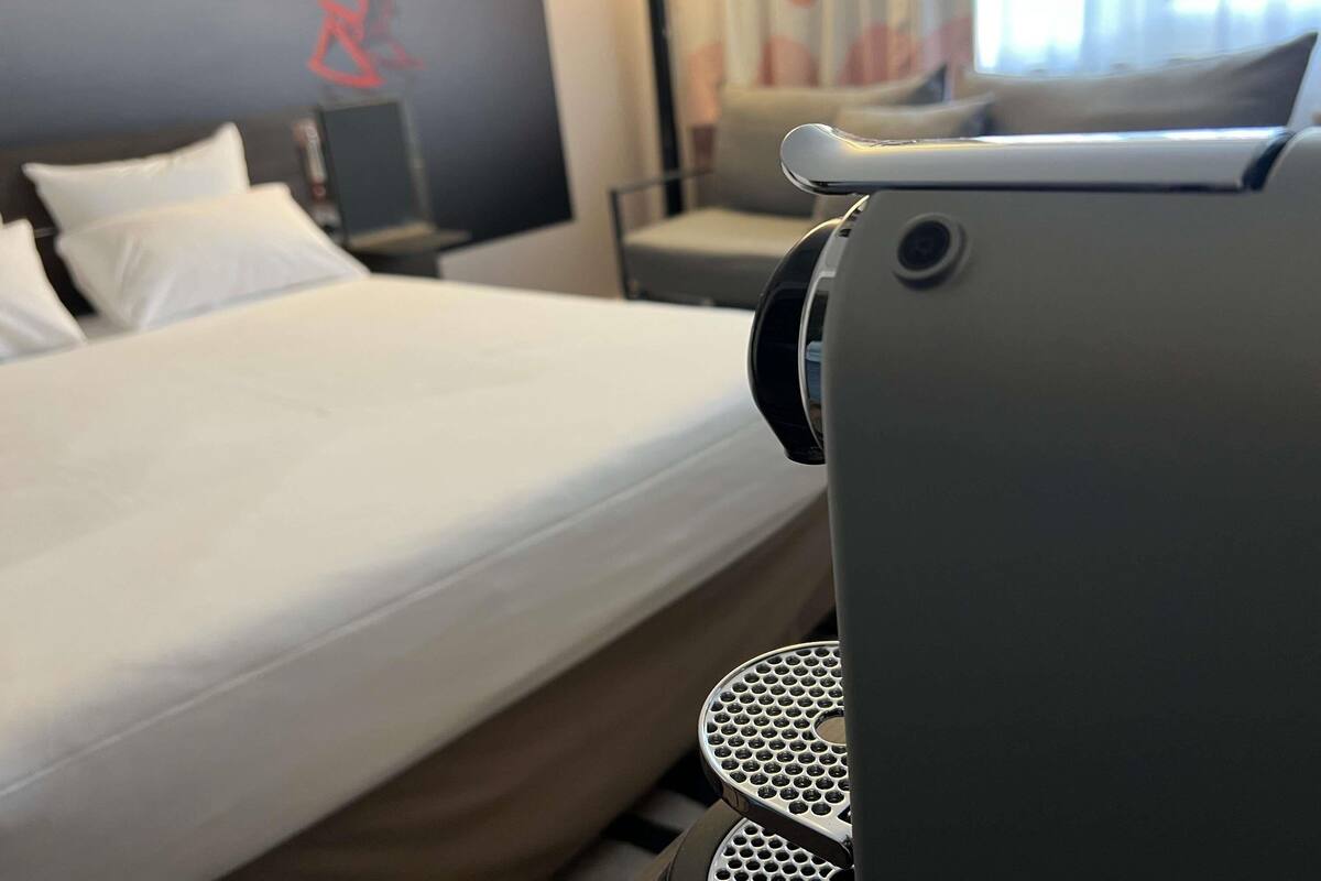 A hotel room with a bed, a desk, and a chair.