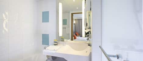 A modern bathroom with a white sink, mirror, and shower area.