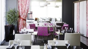 A modern restaurant with purple upholstered chairs, white tables, and a large potted plant. - Novotel Limoges Le Lac (Limoges)