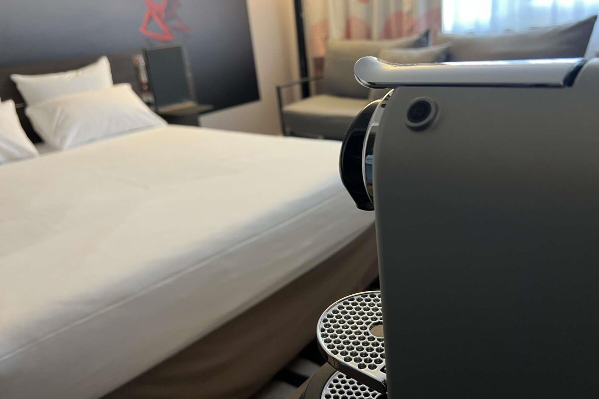 A hotel room with a bed, a desk, and a chair.