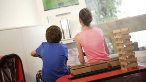 Two people sitting at a table with a television and wooden blocks. - Novotel Limoges Le Lac (Limoges)