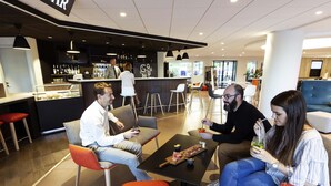 A modern bar area with seating, a bar counter, and a visible menu board. - Novotel Limoges Le Lac (Limoges)