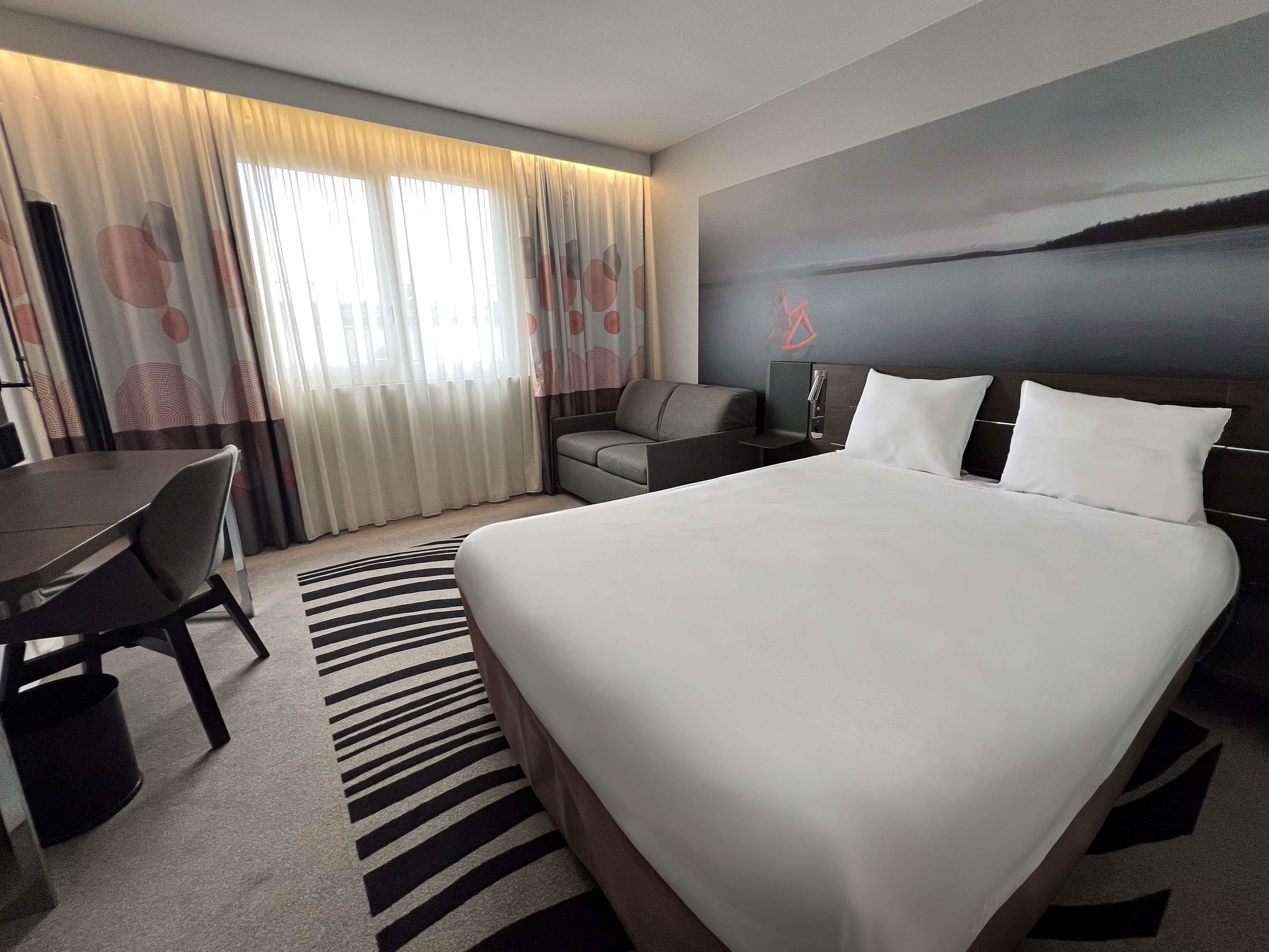 Een moderne hotelkamer met een groot bed, een bureau en een bank.