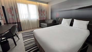 Een moderne hotelkamer met een groot bed, een bureau en een bank.