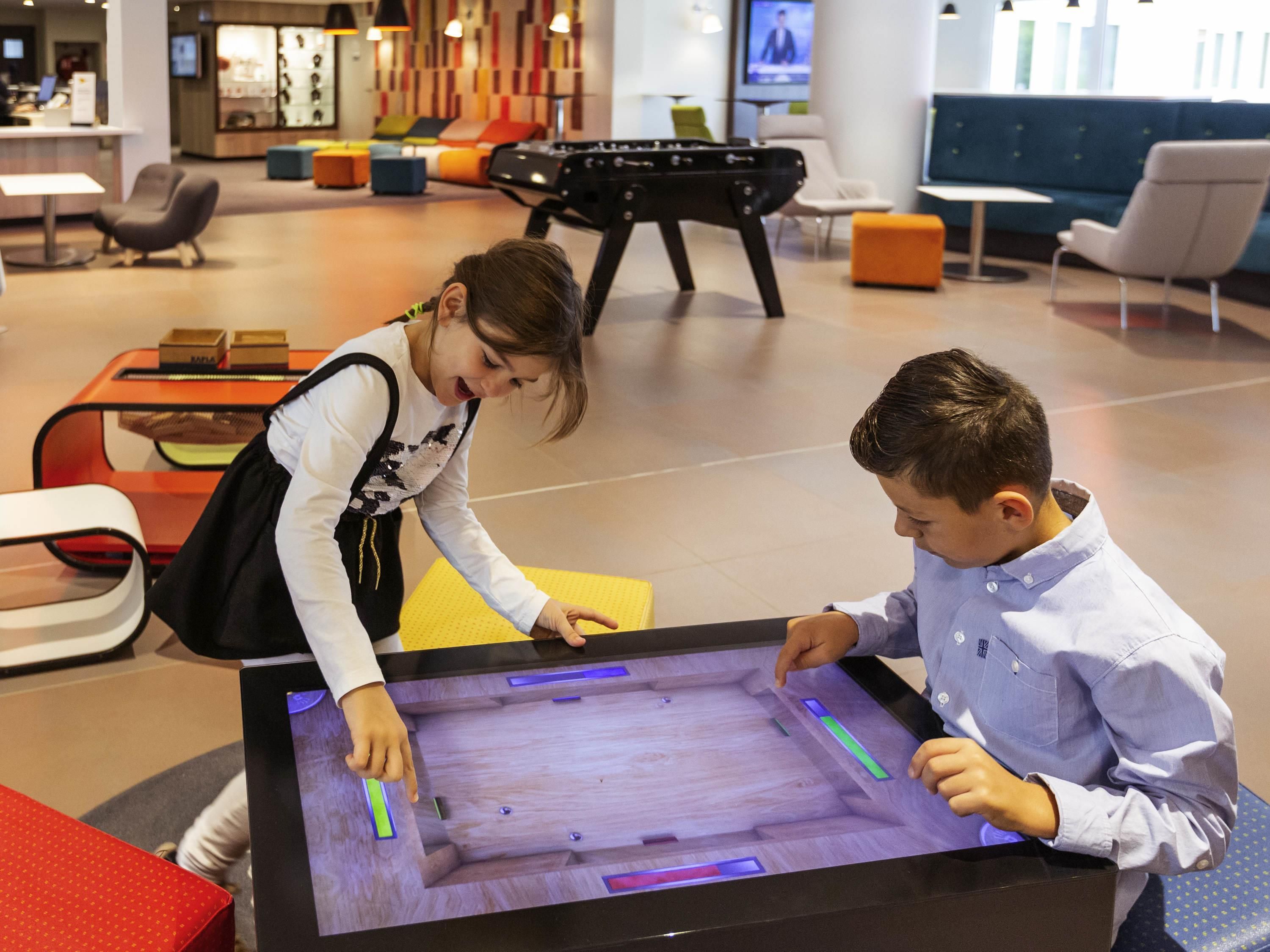 Un enfant et un adulte interagissent avec un écran interactif numérique dans un environnement intérieur moderne.