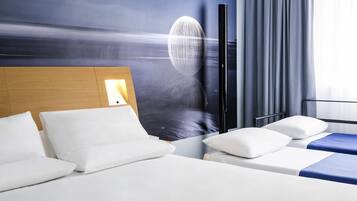 A hotel room with a large wall mural, a wooden headboard, and a bed with white bedding.