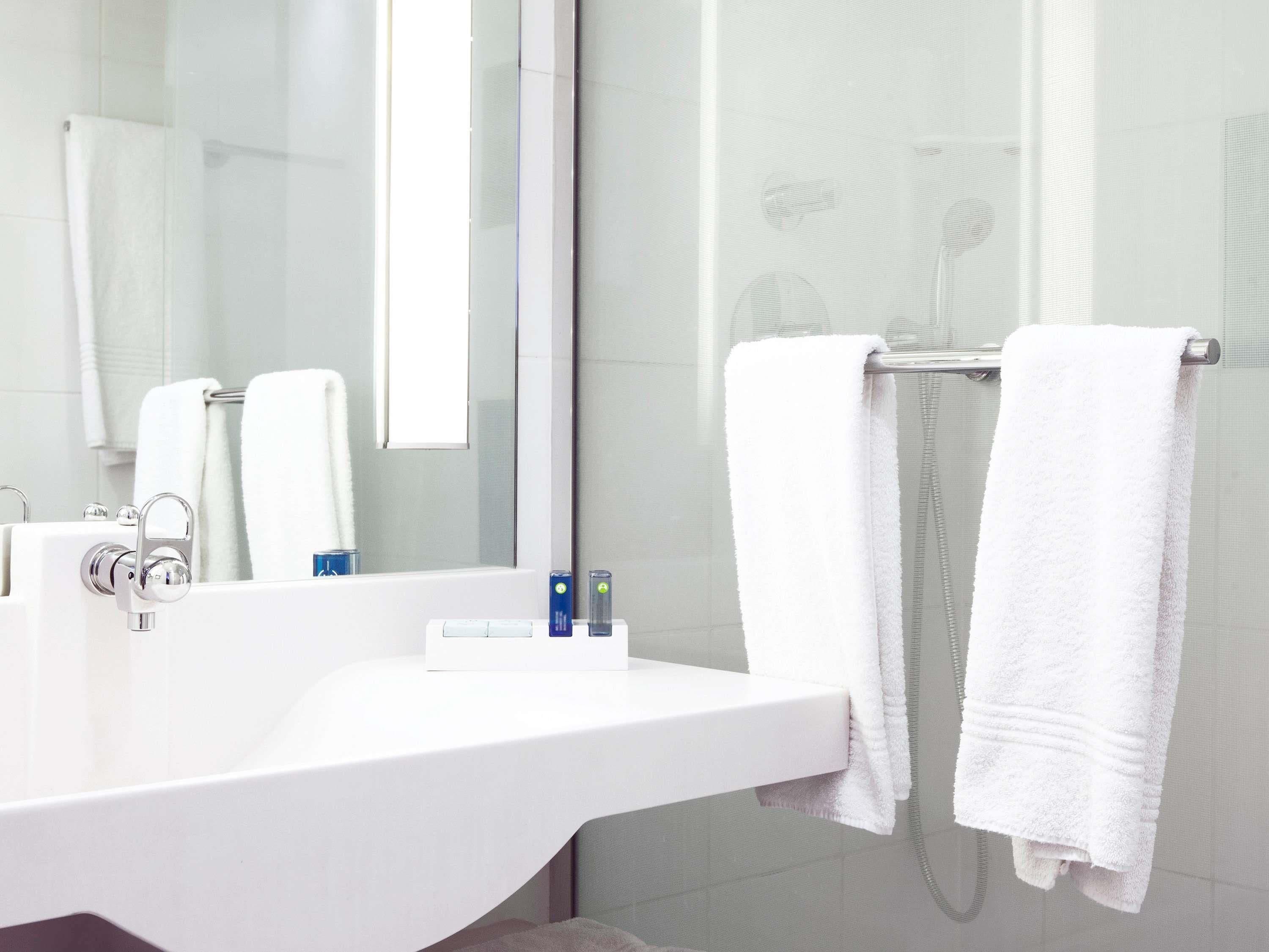 A modern bathroom with a white sink, a mirror, and two towels hanging on a towel rack.