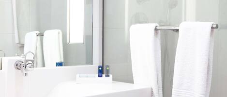 A modern bathroom with a white sink, a mirror, and two towels hanging on a towel rack.