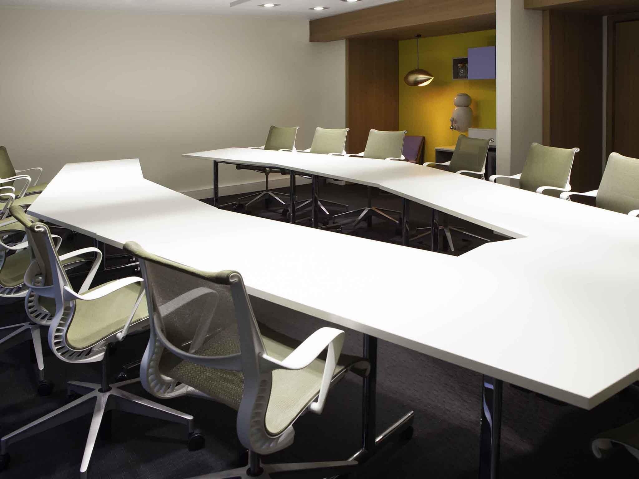 Une salle de conférence avec une longue table et de nombreuses chaises.