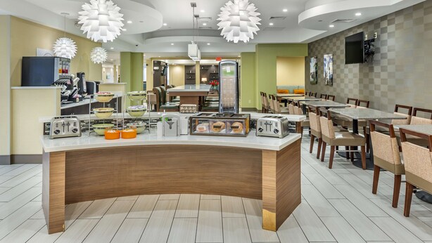 Un restaurante moderno con una barra central, varias mesas y sillas.