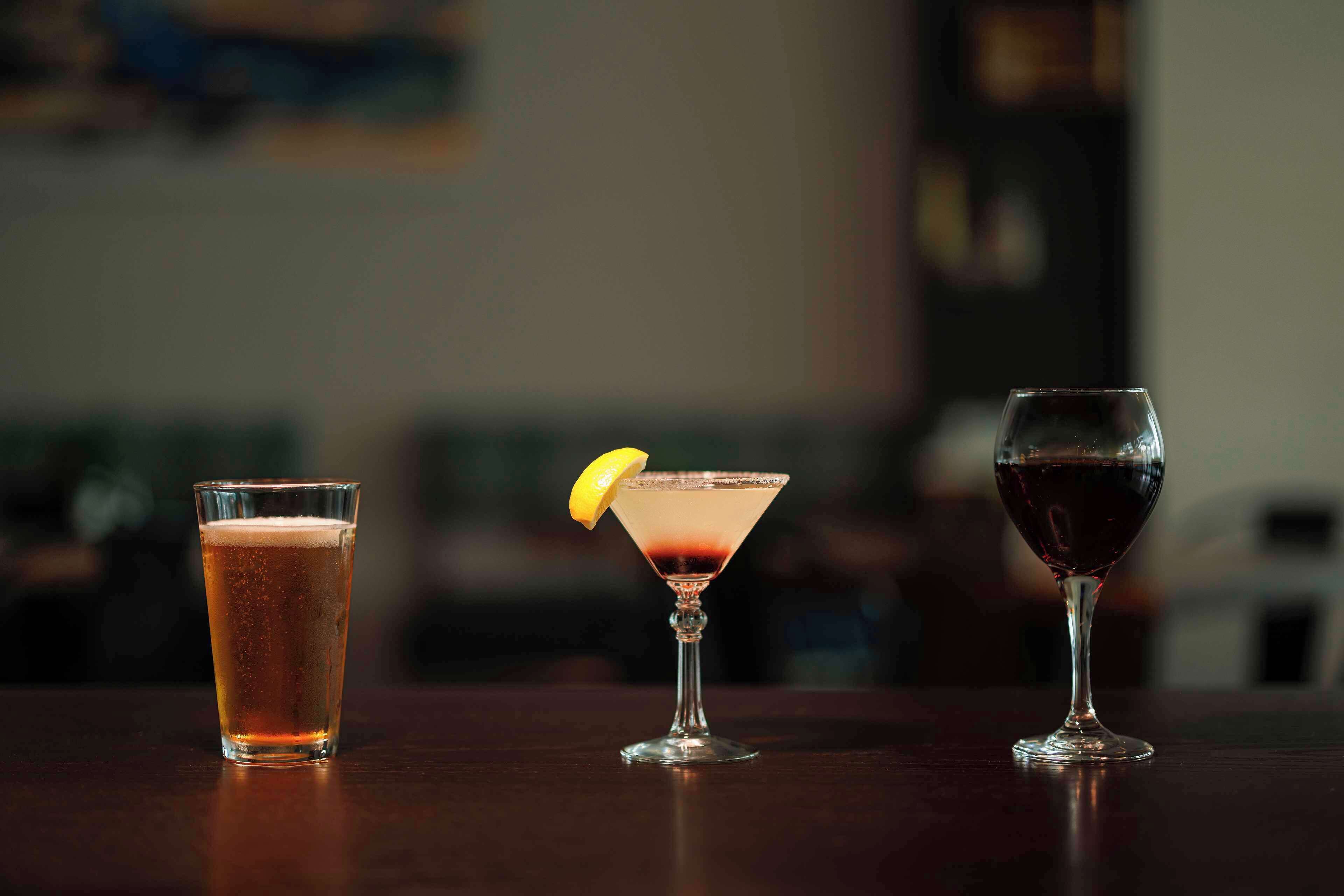 Three glasses of different beverages on a wooden table.