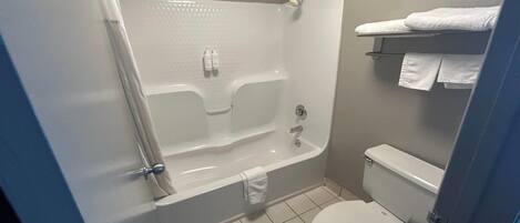 A bathroom with a bathtub, toilet, and towel rack.
