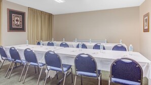 Une salle de conférence équipée de tables, de chaises et de bouteilles d’eau.