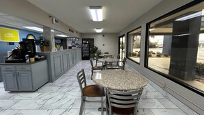 Un hall d’hôtel comprenant un comptoir d’accueil, un espace salon et de grandes fenêtres donnant sur le parking.