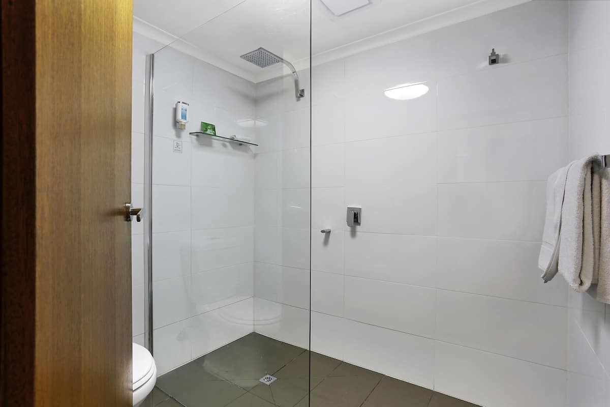 Ein modernes Badezimmer mit Duschkabine aus Glas, Toilette und Handtuchhalter.