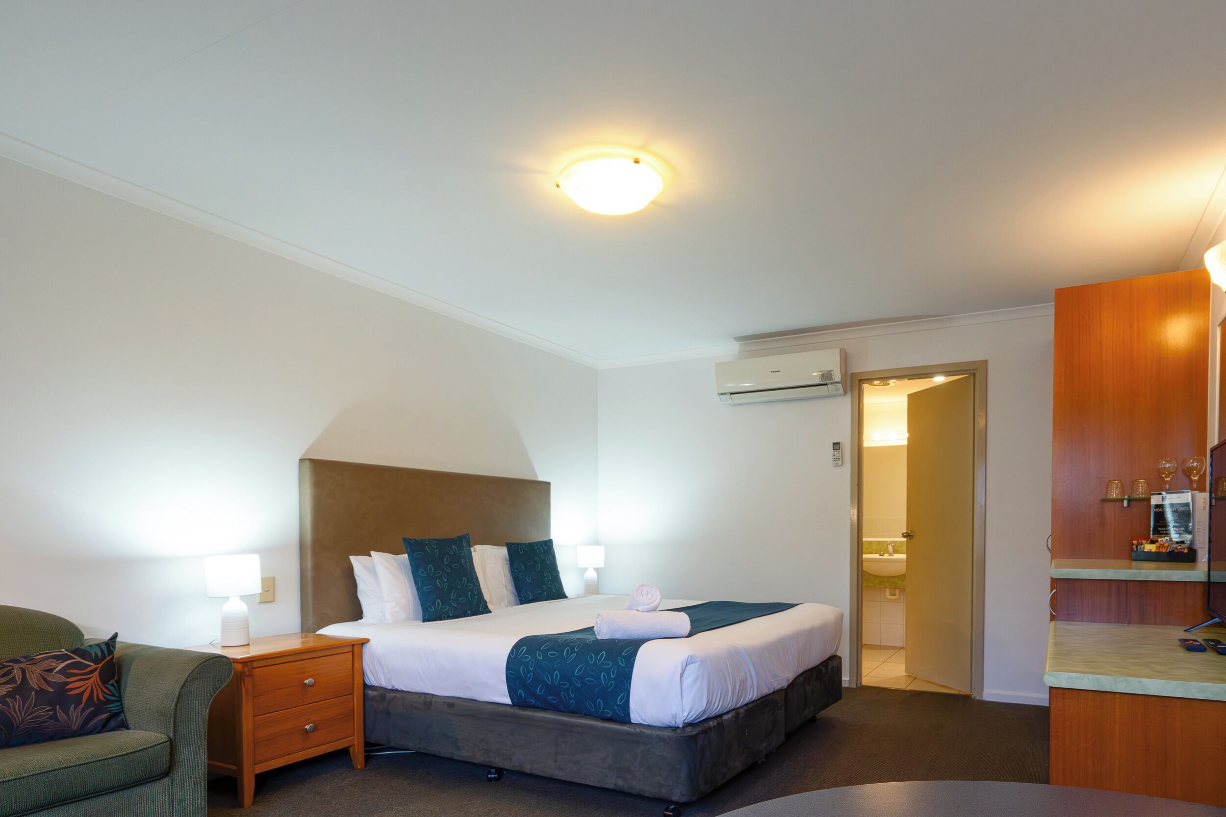 A hotel room with a bed, nightstand, and a small table.
