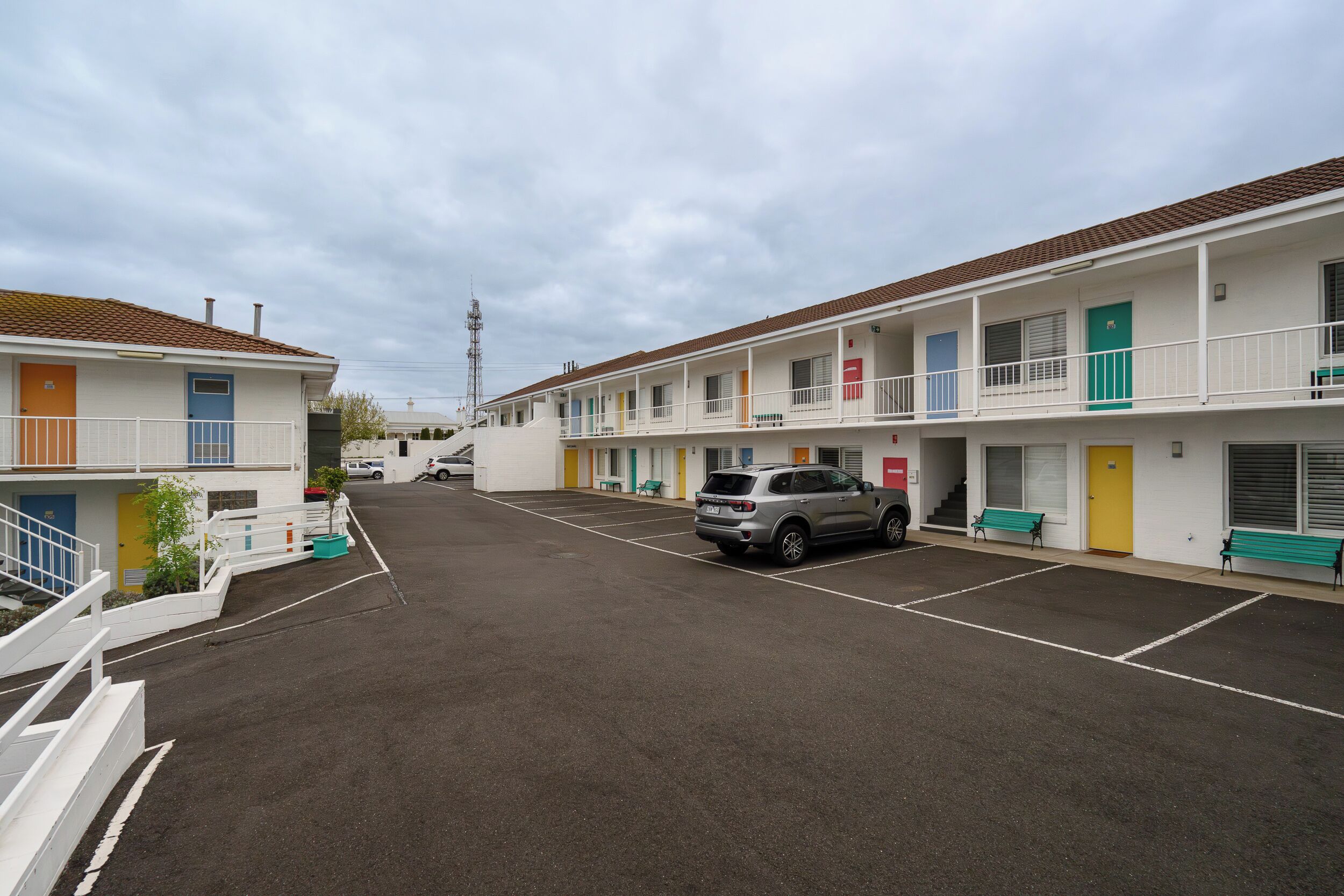 A row of motel buildings with a parking lot in front.