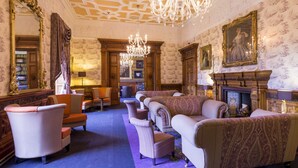 Een luxe kamer met sierlijk meubilair, een weelderige kroonluchter en een open haard.