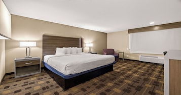 Una habitación de hotel con una cama grande, lámparas de noche, una silla, un escritorio y una ventana con persianas.