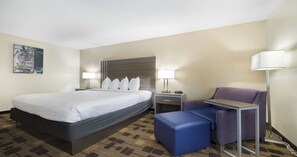 A hotel room with a large bed, two bedside tables with lamps, a small desk, a chair, and a sofa. - Best Western Amador Inn (Jackson)