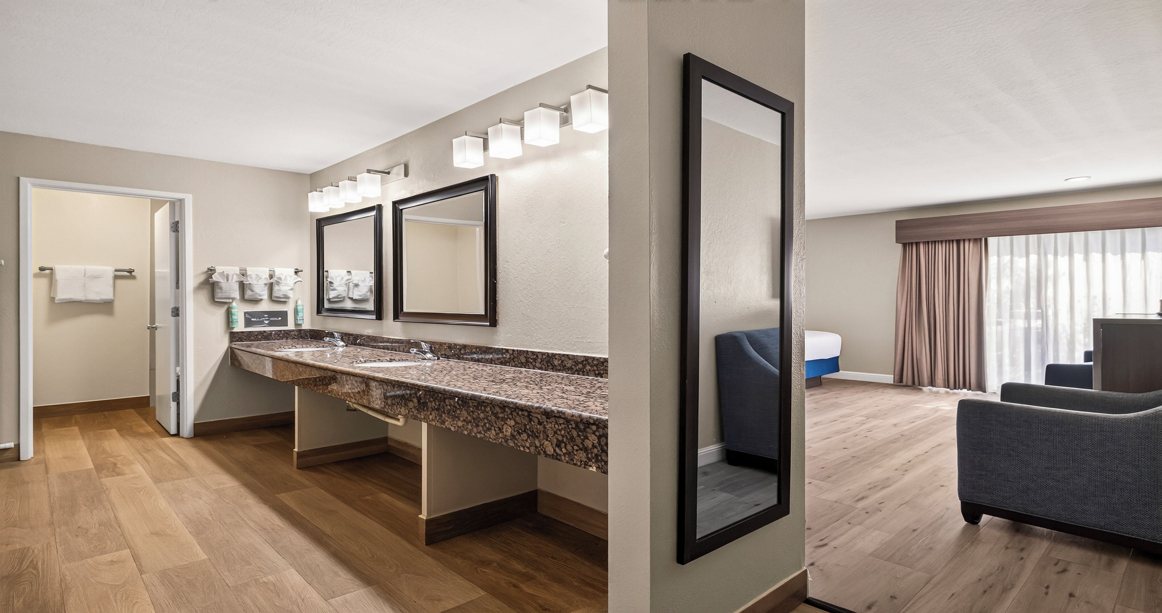 A hotel bathroom with a double sink, mirrors, and a shower area.