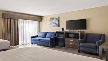 Quarto de hotel com cama, duas poltronas, escrivaninha, televisão de tela plana, cafeteira e micro-ondas.