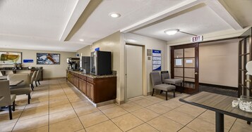 Un vestíbulo de hotel con mostrador de recepción, zona de estar y un panel de menú adherido a la pared.