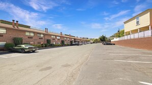 Une rangée de bâtiments en briques, avec un parking devant.