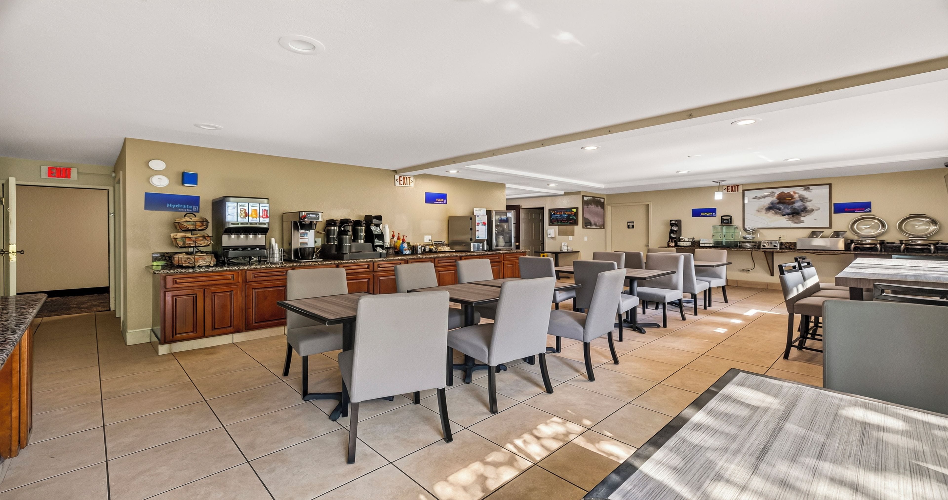 A hotel dining area with a bar, multiple tables, and chairs.
