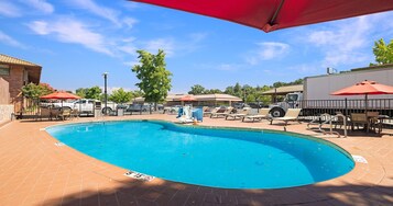 Una piscina al aire libre, sombrillas, sillones reclinables de piscina