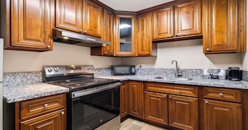 Una cocina con armarios de madera, estufa de acero inoxidable, microondas y fregadero.