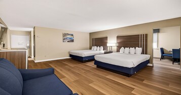 Habitación de hotel con dos camas, un escritorio, una silla y un cuadro en la pared.