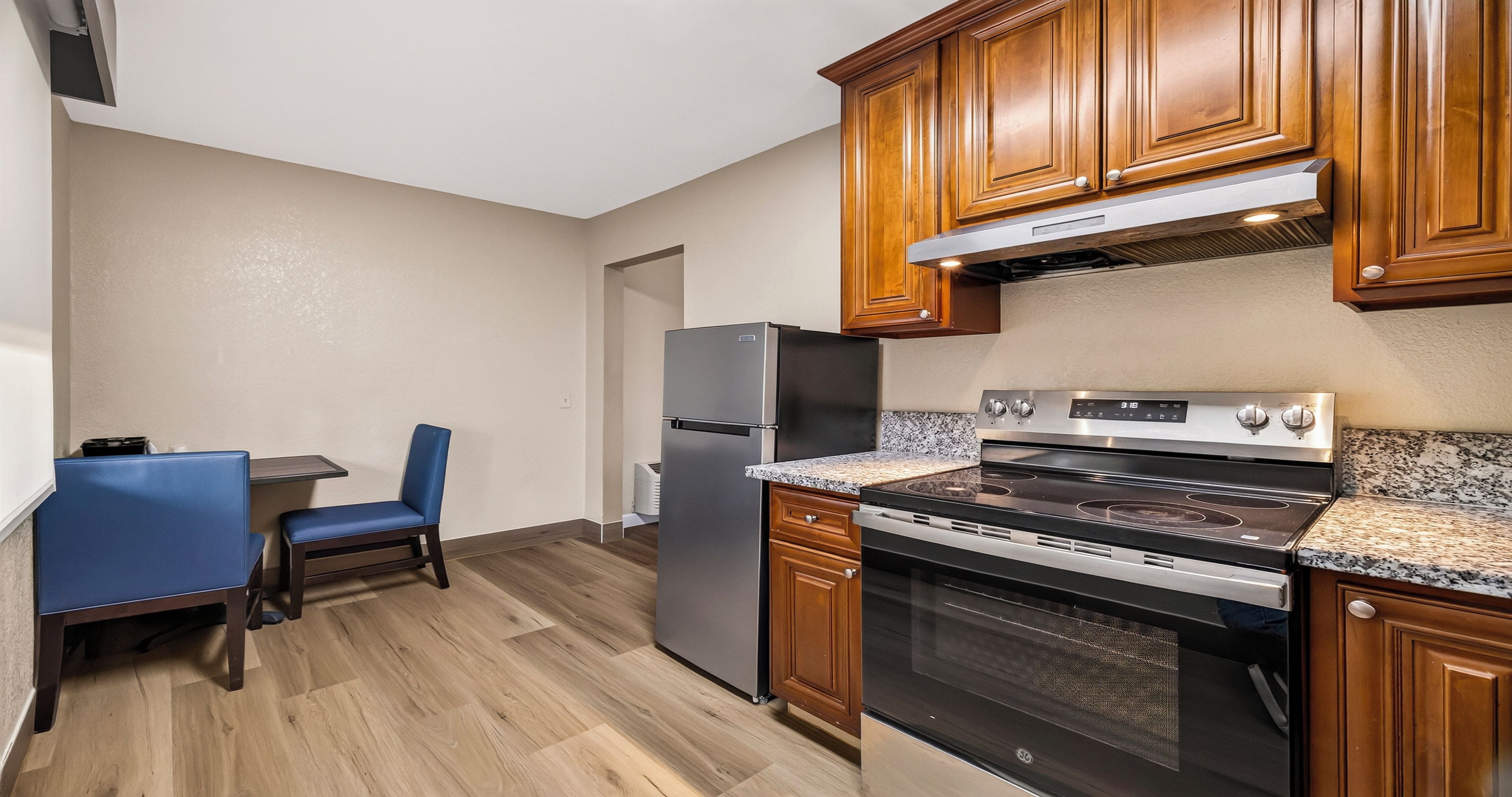 A compact kitchen with wooden cabinets, a built-in oven, and a refrigerator.
