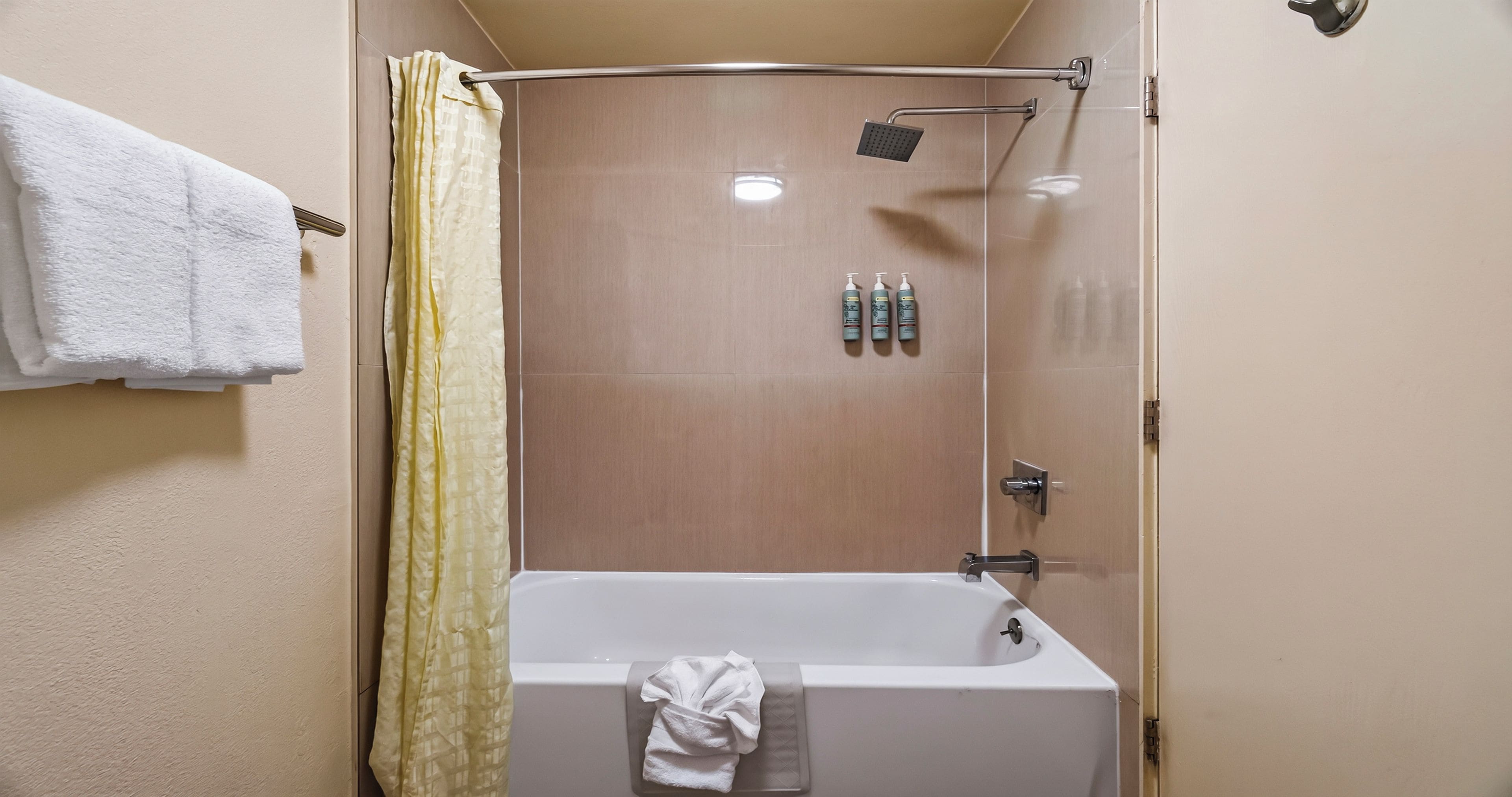 A bathroom with a bathtub, a shower area, and a towel rack.