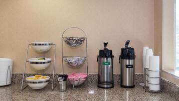 A breakfast bar setup with various containers, including a coffee maker, a thermos, and a basket with papers.