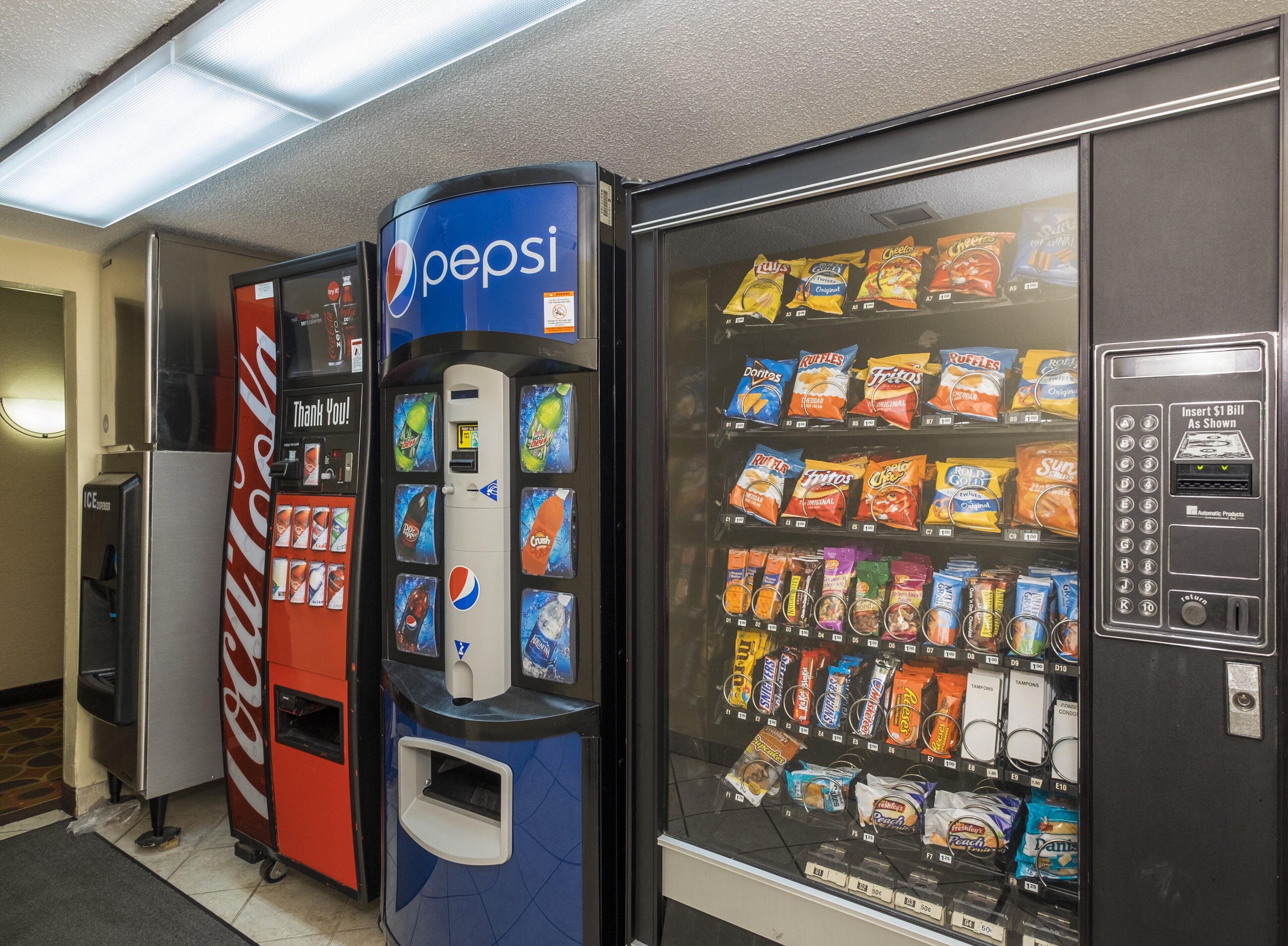 Una máquina expendedora con logotipo de Pepsi, una máquina expendedora de Coca-Cola y otra máquina expendedora de snacks.