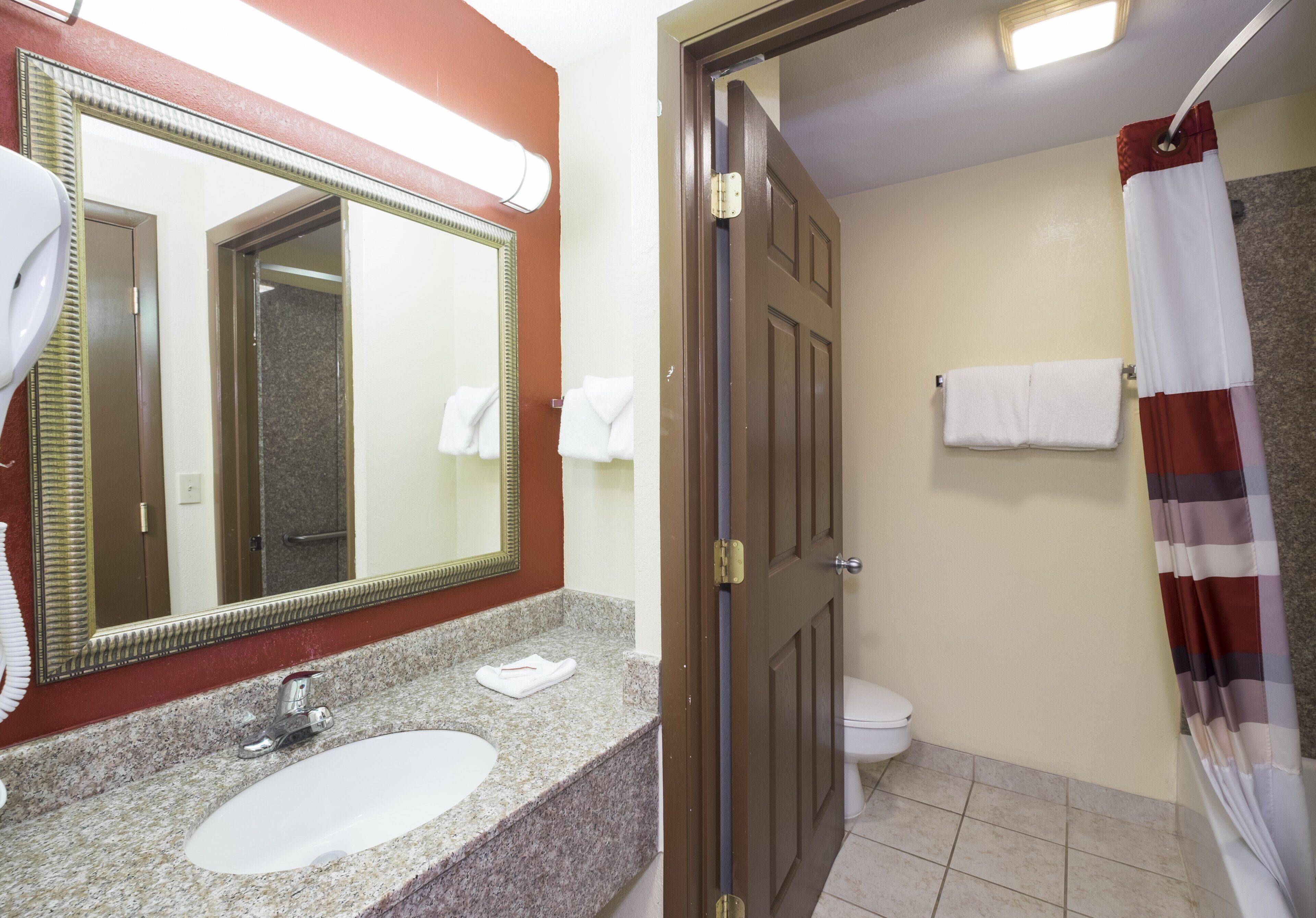 Un baño con lavamanos, espejo, inodoro y cortina de ducha.