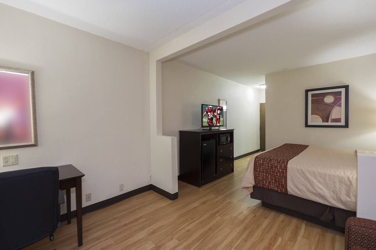 A hotel room with a bed, a desk, a TV, and a cabinet.