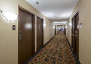 A hotel hallway with doors, a patterned carpet, and a sign indicating room number 216. - Red Roof Inn & Suites Cincinnati North - Mason (Cincinnati)