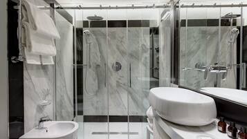 A modern bathroom with a glass-enclosed shower, a white sink, and a vanity with toiletries.