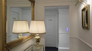 Un pasillo con un espejo grande, dos lámparas y una puerta con el número 305.