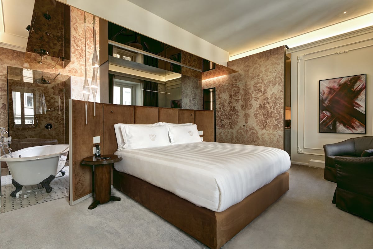 Un dormitorio moderno con una cama grande, una bañera de patas clásicas y un tocador empotrado.