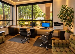 Un espace de bureau moderne comprenant deux bureaux, deux chaises, une imprimante et une grande fenêtre donnant sur des arbres.