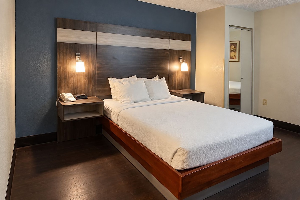 Une chambre d’hôtel avec un lit, des tables de chevet et des lampes fixées au mur.