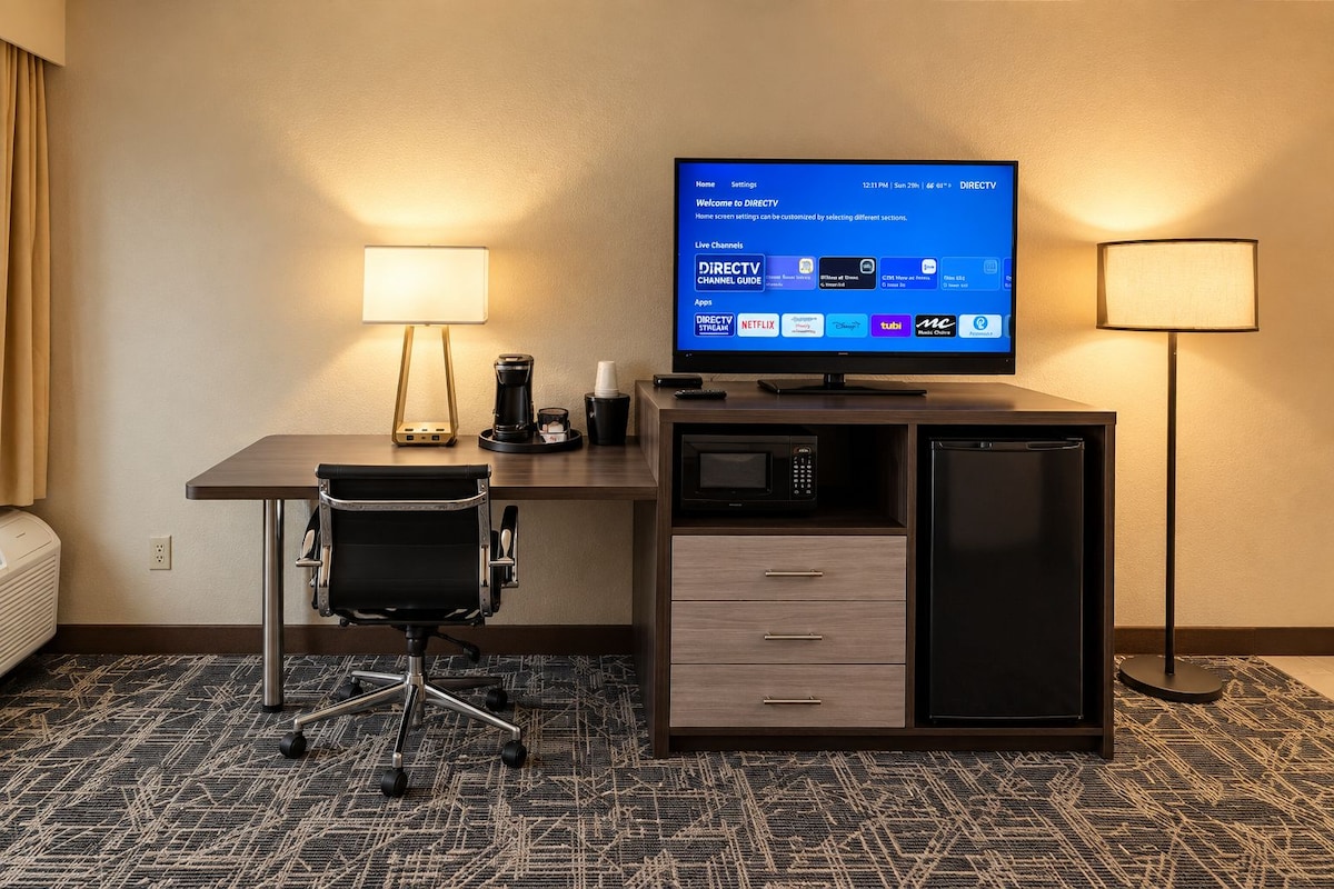 Une chambre d’hôtel équipée d’un bureau, d’une chaise, d’un téléviseur diffusant les chaînes DIRECTV, d’une machine à café, d’un four à micro-ondes et d’un réfrigérateur.