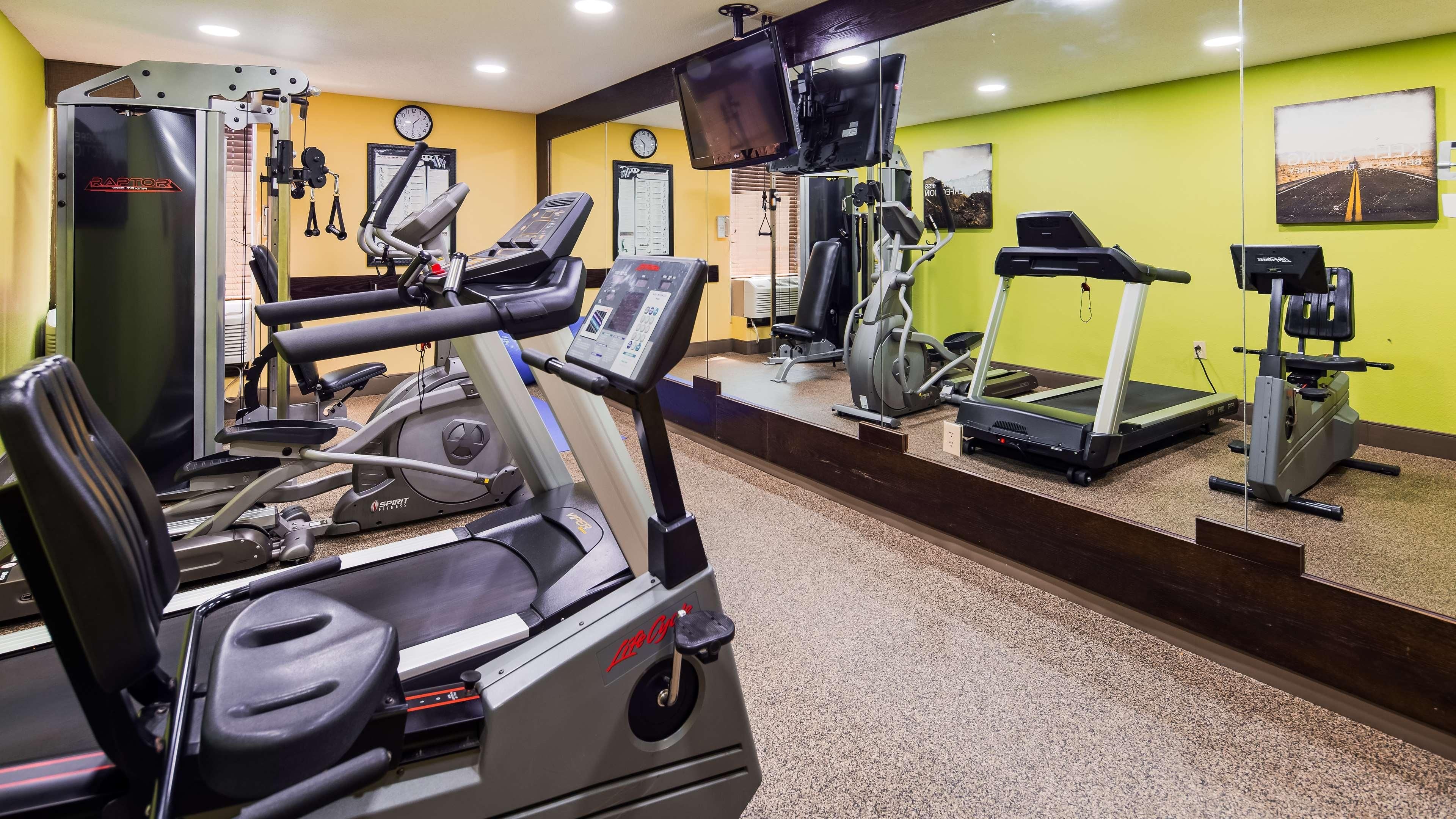 Un gimnasio con equipo de ejercicio variado, incluyendo cintas de correr, una bicicleta estática y máquinas de pesas.